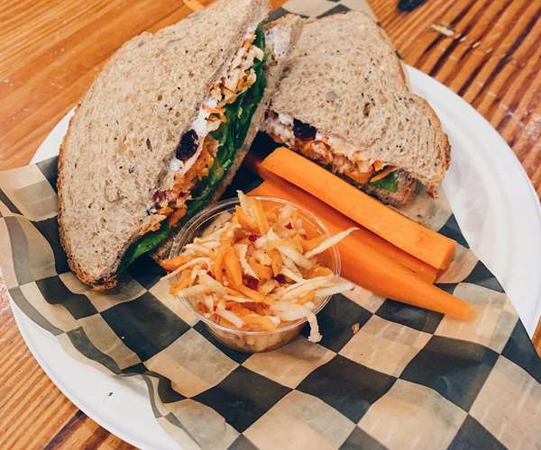 Tasty veggie sandwich with a side of carrots and slaw